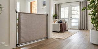 A modern, stain-resistant fabric baby gate installed in a living room doorway.
