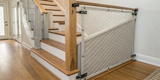 A retractable safety gate installed with hardware at the top of a staircase.