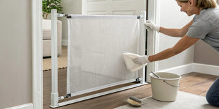 A person cleaning a fabric baby gate by hand with a cloth and a gentle, non-toxic cleaner.